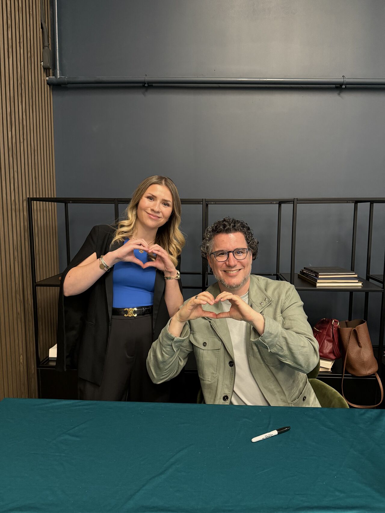 Paige Kaye and Eric Ries making heart shapes with their hands at the post-keynote book signing table